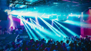 A vibrant crowd at a New York nightclub, surrounded by pulsating music and dazzling bright lights.