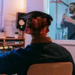 A man in a recording studio with a microphone in front of him, working on TIDAL collabs.