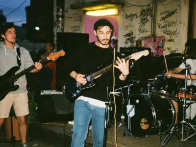 Under a starlit sky, a band performs outdoors, their music echoing against graffiti-covered walls. The guitarist sings passionately alongside the rhythmic beat of the drums and the bass's deep tones. This electrifying scene is perfect for marketing on Instagram, captivating an audience with its raw energy.