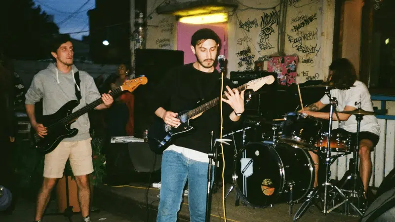 Under a starlit sky, a band performs outdoors, their music echoing against graffiti-covered walls. The guitarist sings passionately alongside the rhythmic beat of the drums and the bass's deep tones. This electrifying scene is perfect for marketing on Instagram, captivating an audience with its raw energy.
