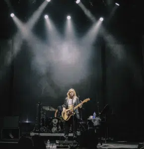 A woman playing a guitar on stage in front of spotlights.