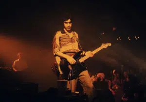 A man playing an electric guitar in front of a crowd.