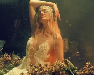 A woman in a white dress posing on a bed of flowers.