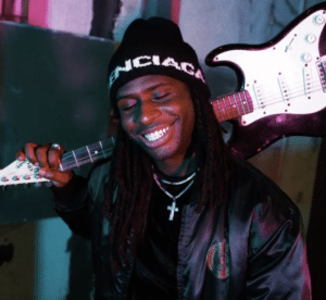 A man holding a guitar and smiling.