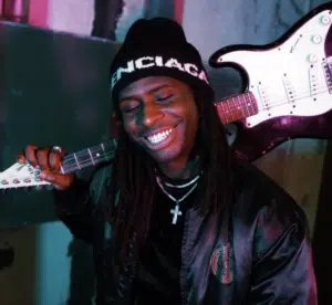 A man holding a guitar and smiling.