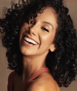 A woman with curly hair smiling for the camera.