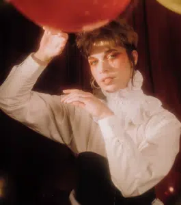 A woman in a white shirt holding a red and gold balloon.