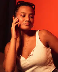 A woman talking on a cell phone in front of an orange background.