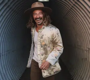 A man wearing a hat and jacket in a tunnel.