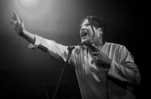 A black and white photo of a person singing into a microphone.