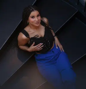 A woman in blue pants posing on a set of stairs.