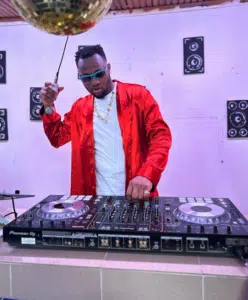 A man in a red jacket is djing at a party.