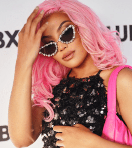 A woman with pink hair and sunglasses posing for a photo.