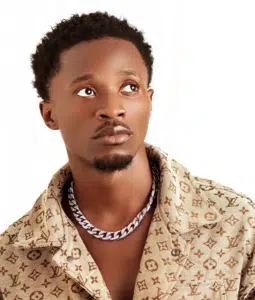 A young man in a tan shirt with a necklace.