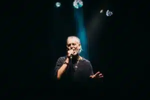 A man with a beard performing fresh new music into a microphone.