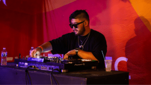 A man in sunglasses playing a DJ set at an event during the best months to release music.