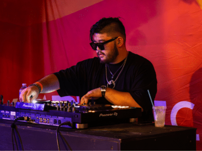 A man in sunglasses playing a DJ set at an event during the best months to release music.