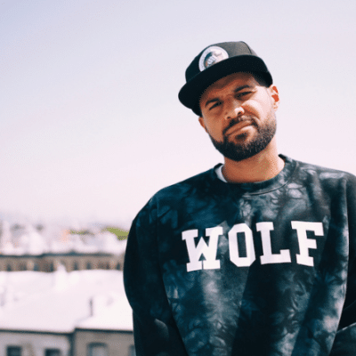 A man wearing a wolf sweatshirt standing on a rooftop, enjoying the fresh new music playing in his ears.
