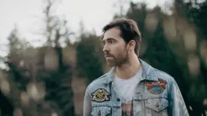 A man in a denim jacket standing in a field.