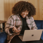 A woman sitting on a couch using a laptop to analyze marketing drivers.