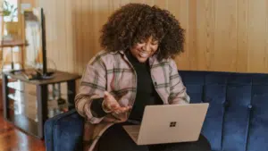 A woman sitting on a couch using a laptop to analyze marketing drivers.