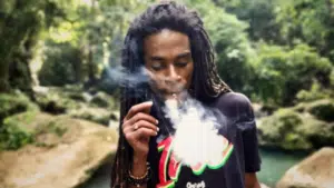 A man with dreadlocks smoking a cigarette.