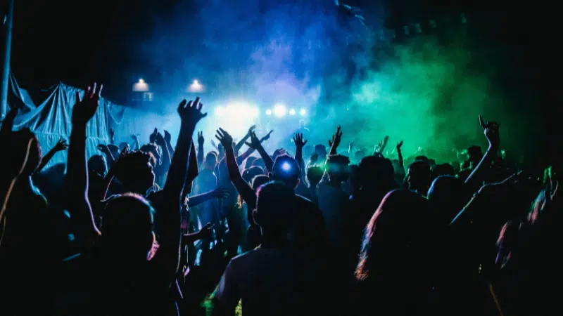 A group of people at a workshop concert with their hands raised.