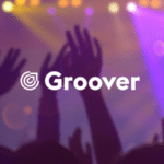 Hands raised at a music promotion concert with colorful stage lights, featuring the logo "groover" foregrounded.