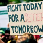 A group of people are holding a sign that reads, "Fight today for a better tomorrow," at a protest or rally.