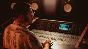 A person meticulously managing the metadata on an audio mixer in a professional recording studio, with large speakers resonating in the background.