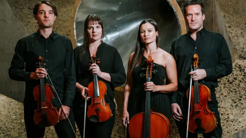 Four people stand unfiltered, holding string instruments against an abstract background.