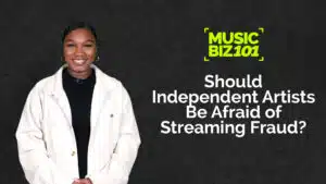 A person in a white jacket stands against a dark background with text: "MUSIC BIZ 101: Should Independent Artists Be Afraid of Streaming Fraud?