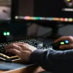 A person is immersed in their work at a computer desk, using a keyboard and mouse while two monitors display dynamic content. Spatial audio enhances the experience, creating an enveloping soundscape that complements the visual engagement.