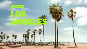 Amidst the palm trees and sunbathers at a vibrant beach, "Symphonic Los Angeles" stands out in bold green text, capturing the city's harmonious blend of culture and nature.