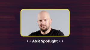 A bald man with a beard is shown in a framed box with the text "A&R Spotlight" below. The background is dark with a gradient design.