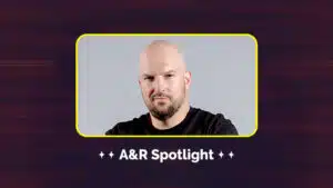 A bald man with a beard is shown in a framed box with the text "A&R Spotlight" below. The background is dark with a gradient design.