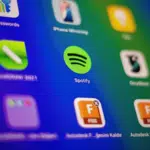 A close-up view of a digital screen displays various app icons, including Spotify and its Spotify Wrapped feature, on a colorful gradient background.