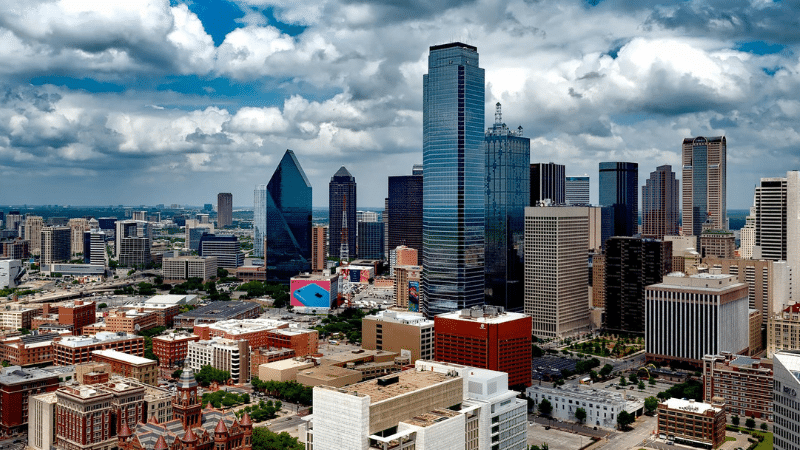 Aerial view of a modern city skyline with tall skyscrapers and cloudy sky above.