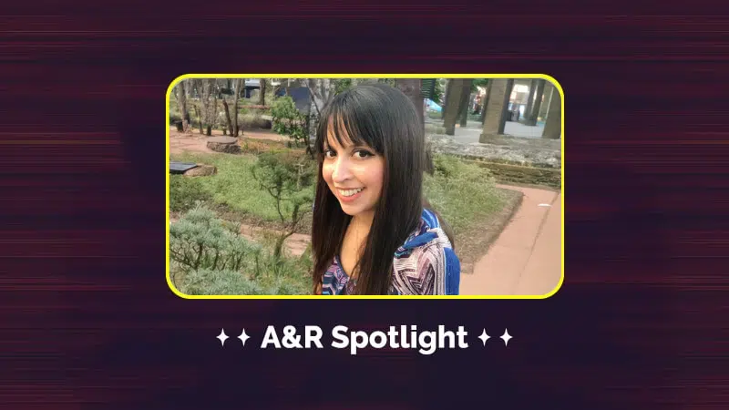 A person with long dark hair smiles outdoors in a garden, embodying the warmth and connection of our community. The text "A&R Spotlight" graces the bottom of the image, inviting you to meet our team.