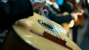 Close-up of a person playing a guitar, as if preparing for a musical conference. The focus is on the strings and body of the instrument, with blurred background elements enhancing the sense of intimate practice before a big performance.