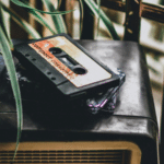 How to Know When You’re Ready to Print Physical Music A cassette tape labeled "compact cassette" rests on top of a vintage radio, with plant leaves partially visible in the foreground.