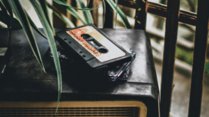How to Know When You’re Ready to Print Physical Music A cassette tape labeled "compact cassette" rests on top of a vintage radio, with plant leaves partially visible in the foreground.