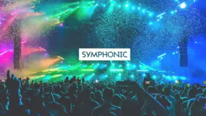 A large crowd at a concert with colorful stage lights and confetti; "SYMPHONIC" is written in bold text at the center.