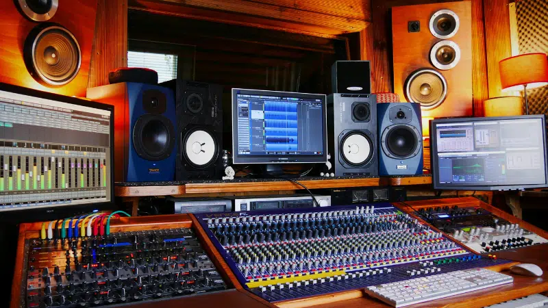 A professional recording studio setup featuring multiple monitors, audio mixing consoles, speakers, and various audio equipment in a wood-paneled room—ideal for artists and label sessions.