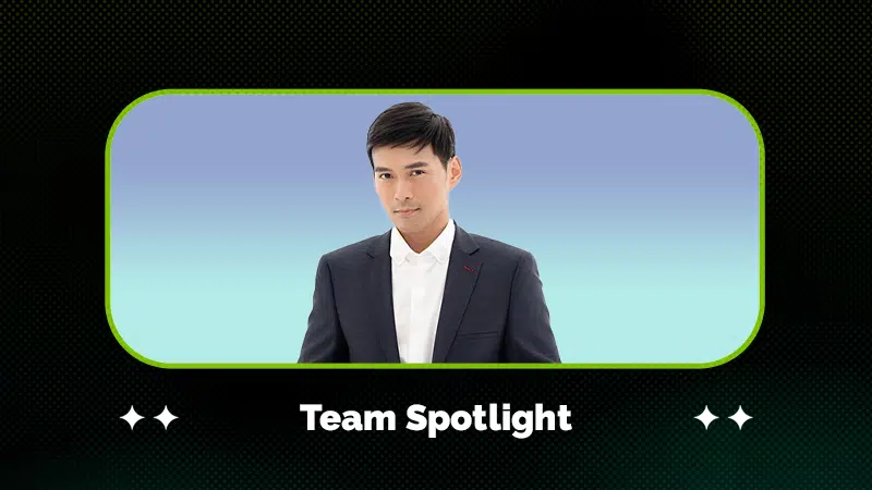 A person in a dark suit and white shirt stands against a blue gradient background, framed by a graphic with the text "Team Spotlight" below.