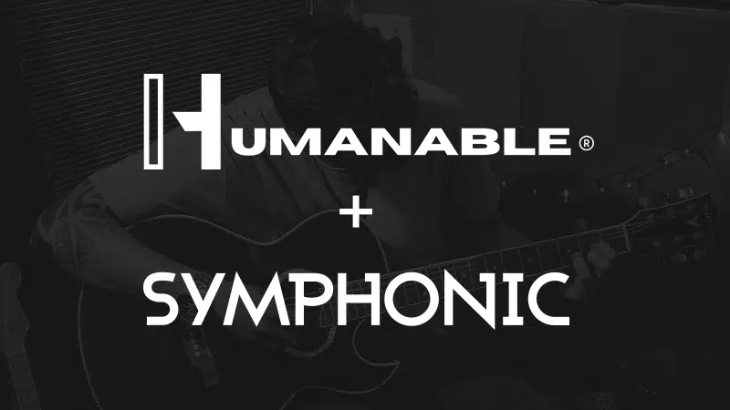 An artist playing an acoustic guitar with the words "HUMANABLE + SYMPHONIC" overlaid in bold white text.