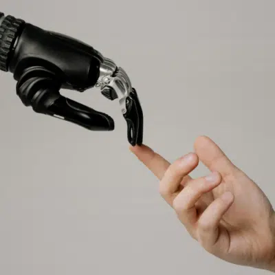 A robotic hand and a human hand reach toward each other, with their fingers nearly touching against a plain background, symbolizing the intersection of technology and humanity in a scene reminiscent of iconic copyright imagery.