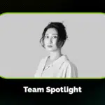 Black and white portrait of a woman with an updo hairstyle, wearing a collared shirt, framed above the text "Team Spotlight" on a dark patterned background.