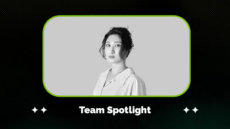Black and white portrait of a woman with an updo hairstyle, wearing a collared shirt, framed above the text "Team Spotlight" on a dark patterned background.