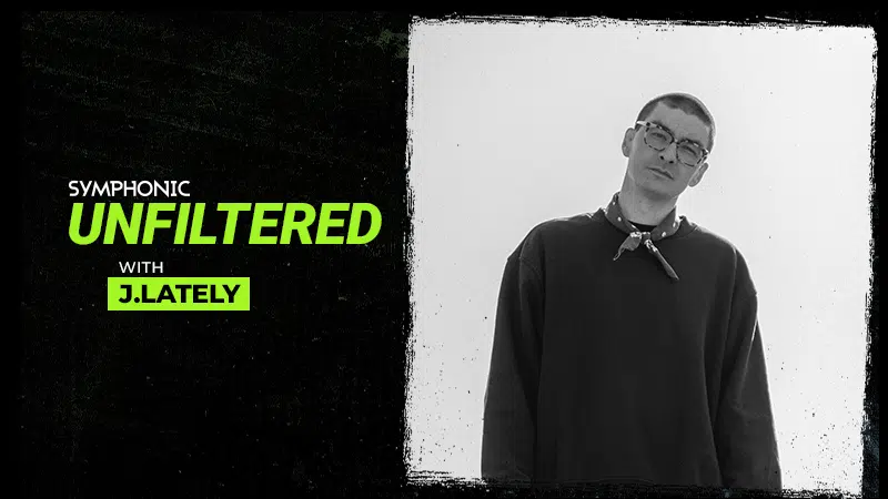 Black and white photo of J.Lately wearing glasses and a sweatshirt, next to text: "Symphonic Unfiltered with J.Lately" on a textured black background, capturing an unfiltered moment.